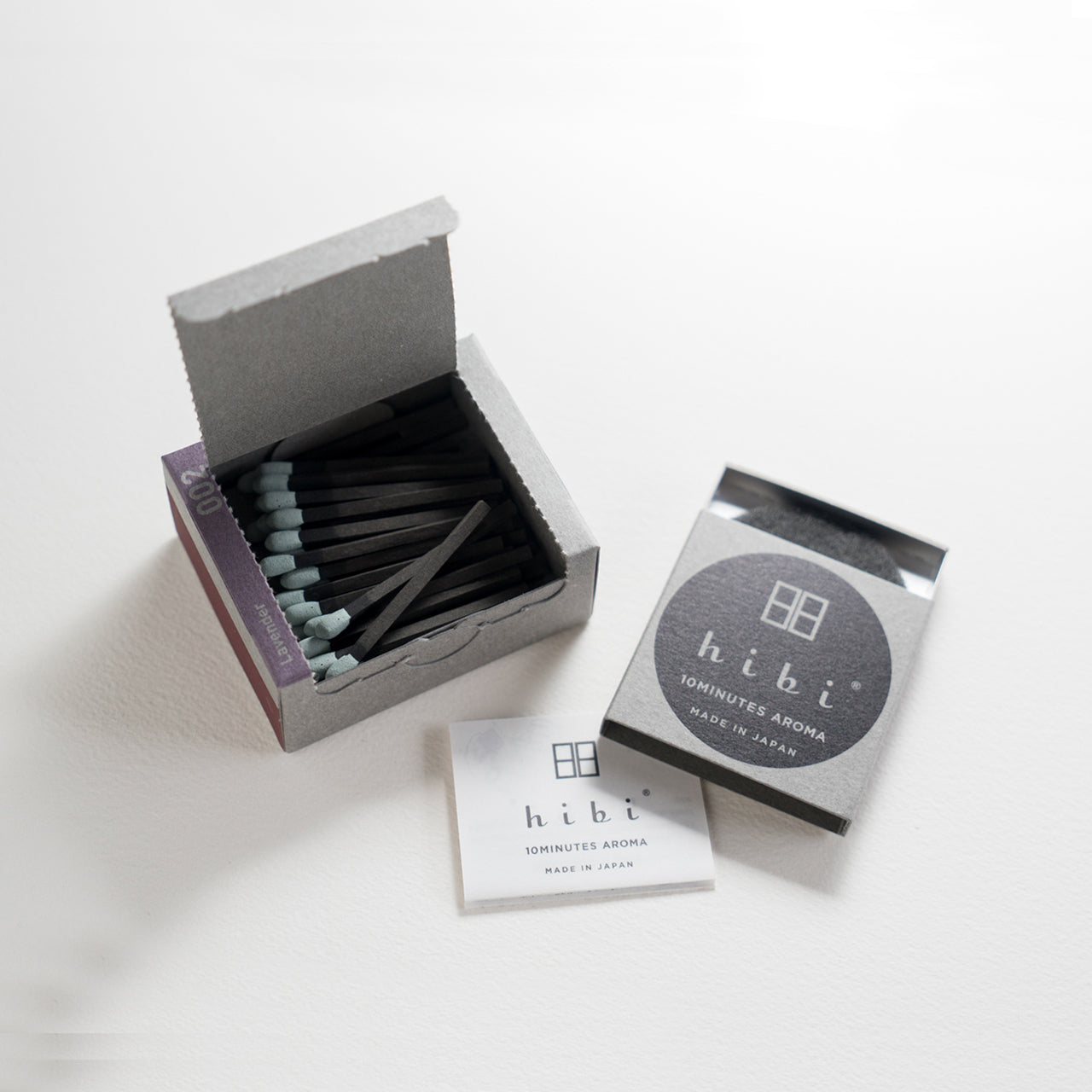 An opened box of Hibi 10 Minutes Aroma Lavender incense matches containing 30 incense sticks with yellow tips. Next to it is a box containing a non-flammable incense mat. All set in a white background.