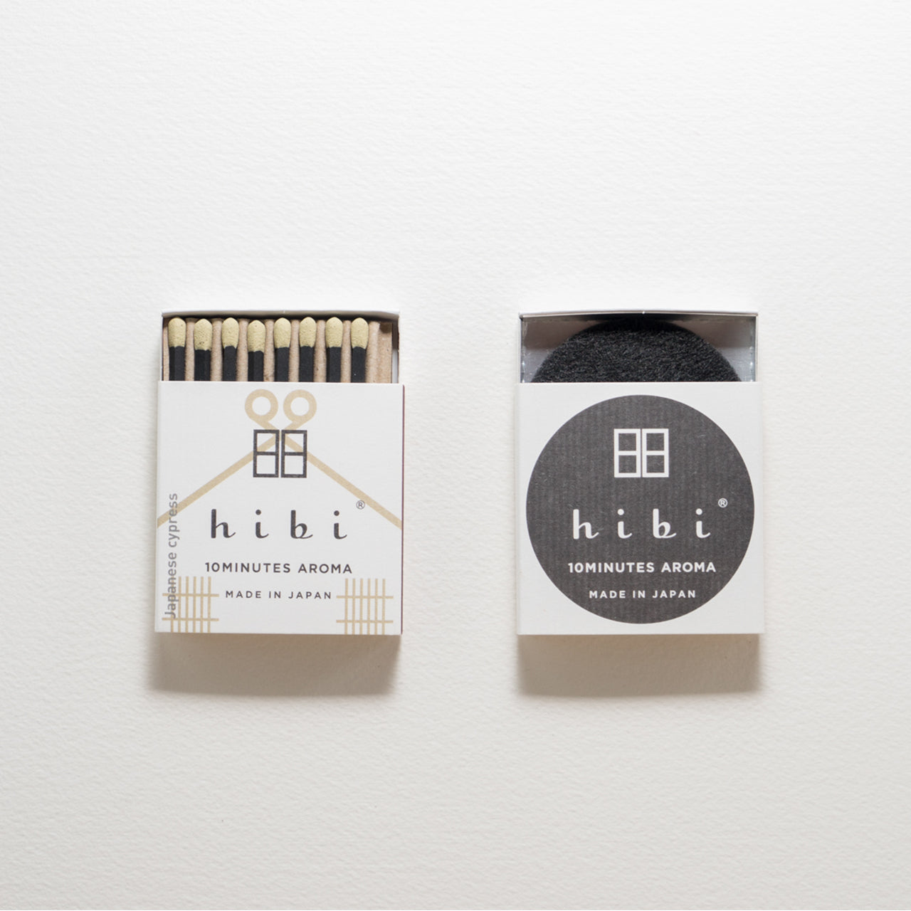 An opened box of Hibi 10 Minutes Aroma Japanese Cypress incense matches which contains 8 incense sticks with yellow tips. Sitting next to it is a box containing a non-flammable mat. All set in a white background.