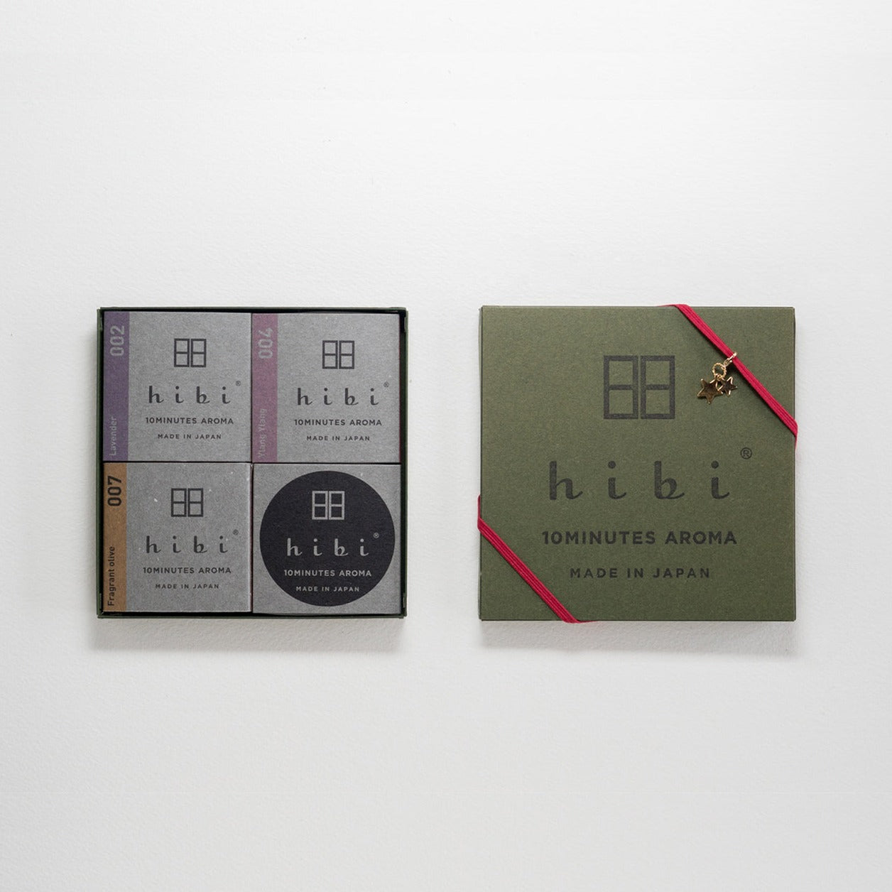 An opened goose-green colour Hibi 10 Minutes Aroma gift box containing three packs of Lavender, Ylang Ylang, and Osmanthus incense matches, and a non-flammable incense mat. The gift box cover is wrapped with a red ribbon and a golden star charm.