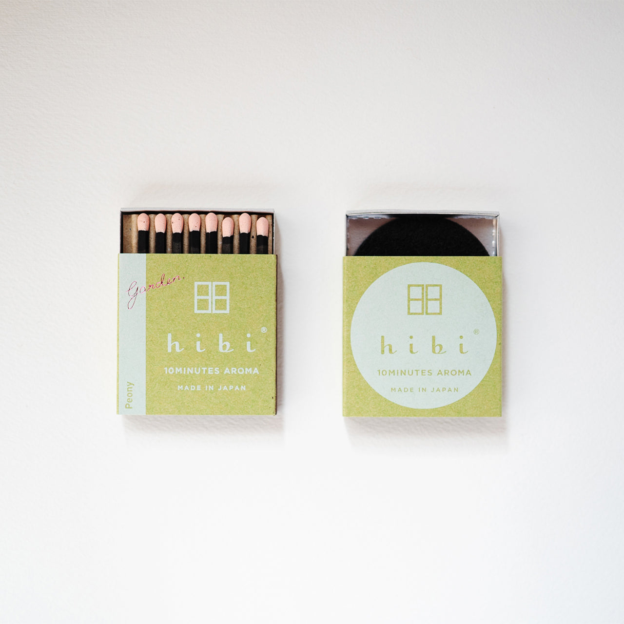 An opened box of Hibi 10 Minutes Aroma Peony incense matches containing 8 incense sticks with pink tips, and a box containing a non-flammable mat. All set in a white background.