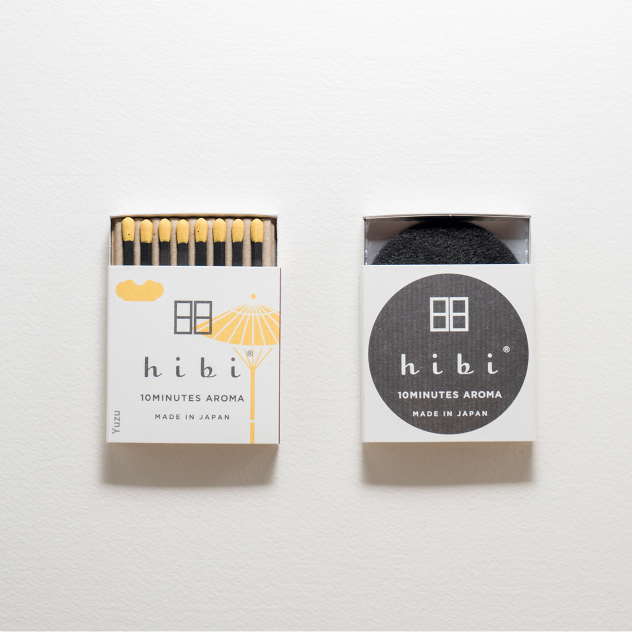 An opened box of Hibi 10 Minutes Aroma Yuzu incense matches which contains 8 incense sticks with yellow tips. Sitting next to it is a box containing a non-flammable mat. All set in a white background.