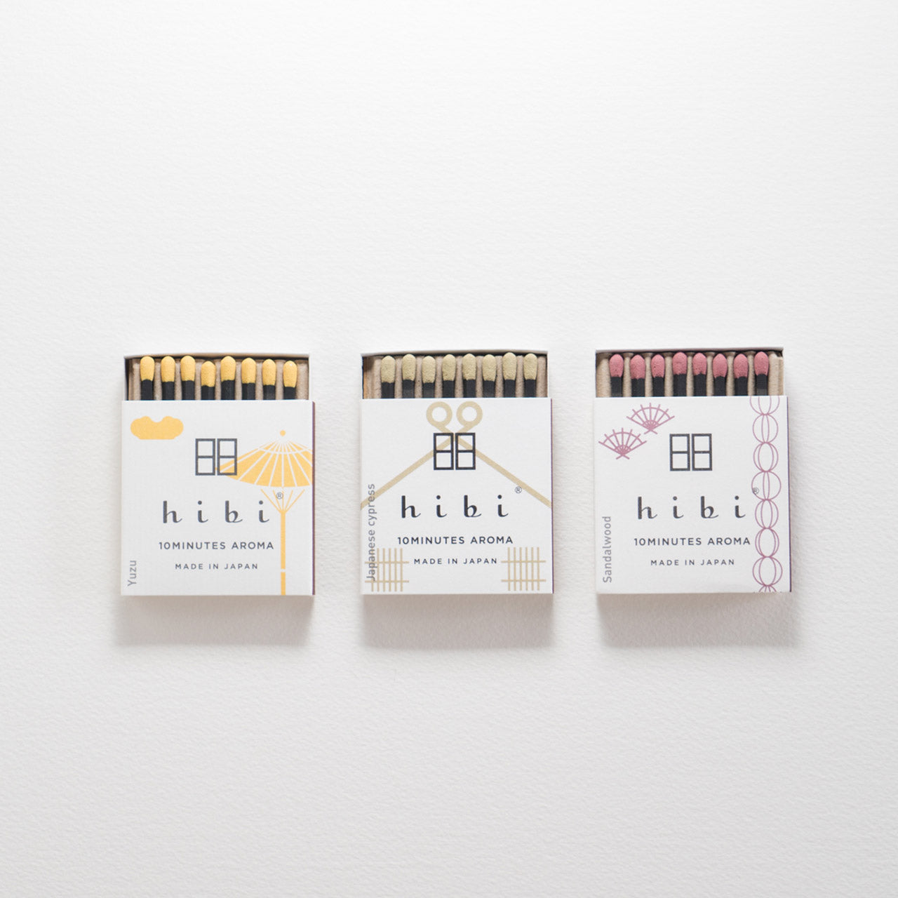Set on a white background are three opened box of Hibi 10 Minutes Aroma incense matches each contains 8 sticks of incense matches with colourful tips. There is also a box containing a non-flammable incense mat.