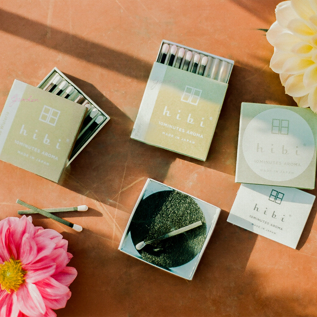 Two opened boxes of Hibi 10 Minutes Aroma garden incense matches, and a burning incense resting on a non-flammable mat.