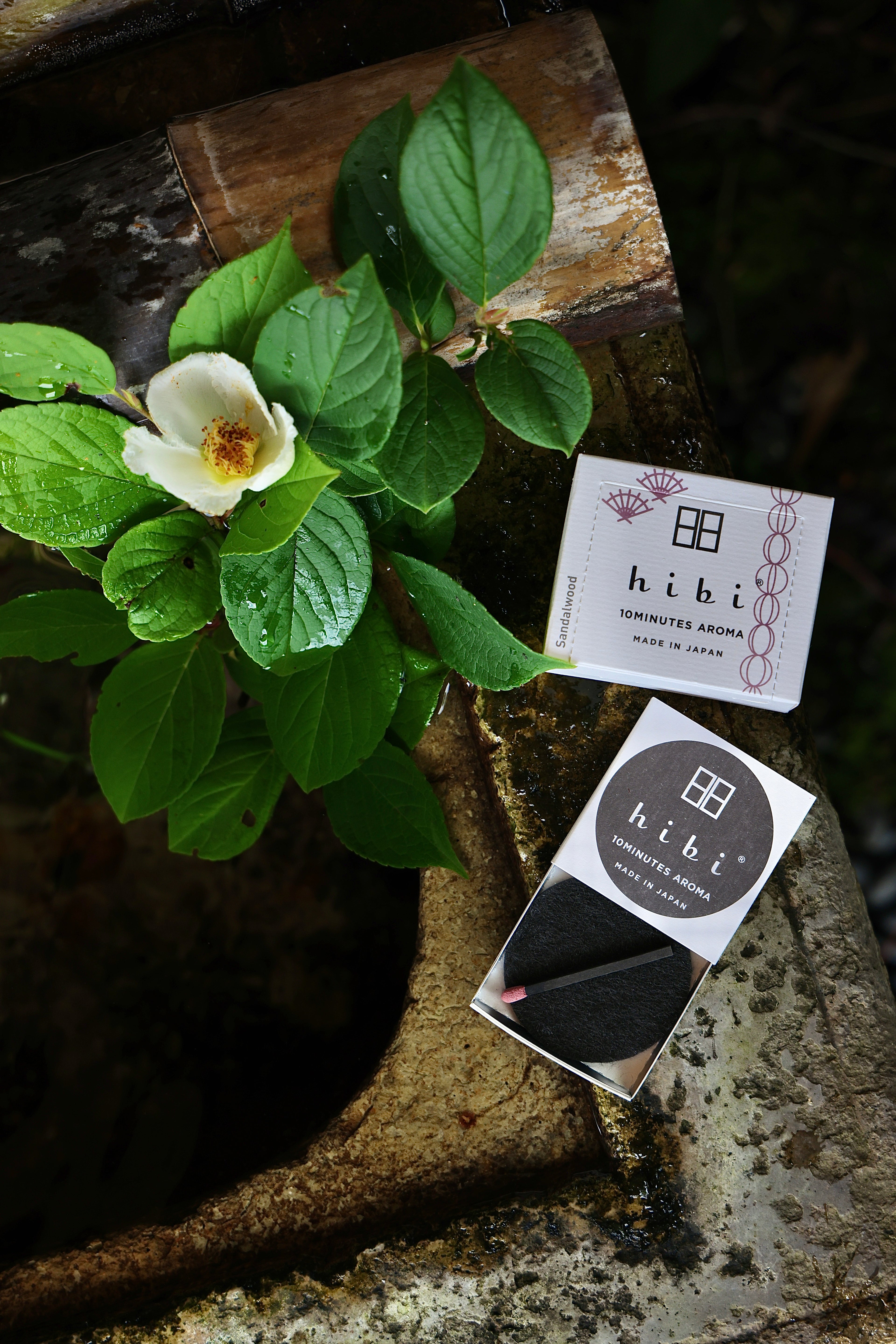 Flower and green leaves on a beside the hibi Sandalwood incense box